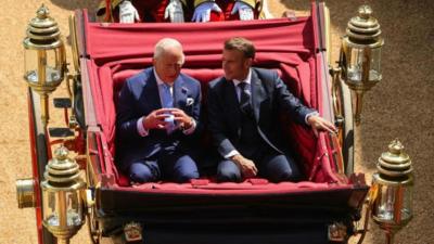 King Charles and Macron, both wearing suits, in a carriage