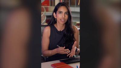 BBC Verify correspondent Merlyn Thomas with long dark hair at an office desk