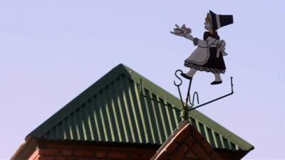 Weather vane of woman in Welsh costume with teapot