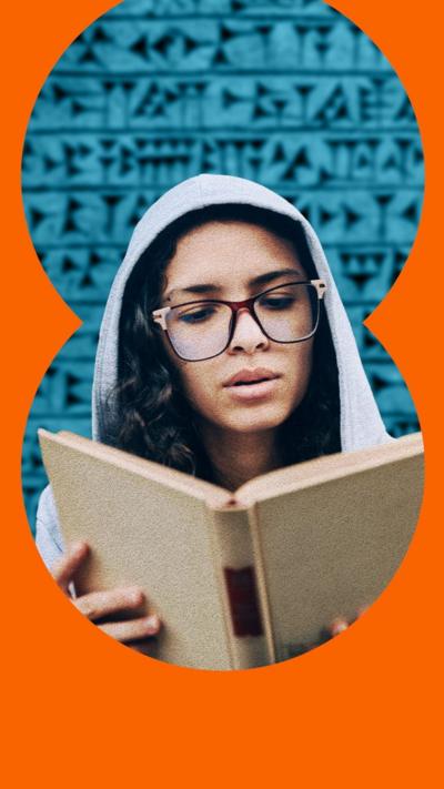 A woman with glasses and a hoodie reads a book
