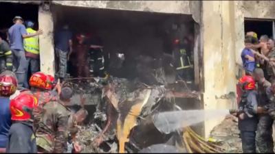 Firefighters spray water on building wreckage