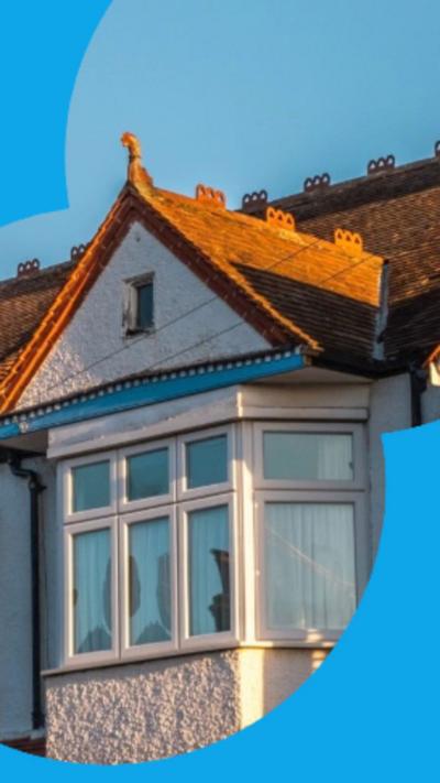 The top floor and roofs of some terraced houses, beneath a blue sky