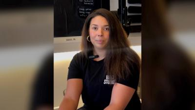 A woman with brown hair wears a black t shirt
