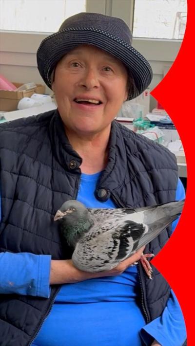 Gudrun Stürmer in a hat and blue top, holding a pigeon