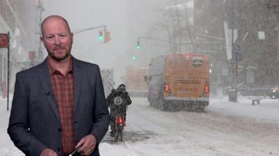 Darren Bett standing in front of a picture of a very snowy road in the US
