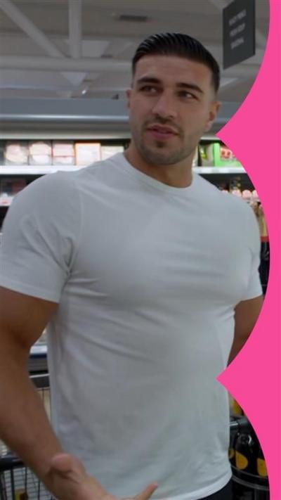 Tommy Fury, in a white T-shirt, stands in a supermarket