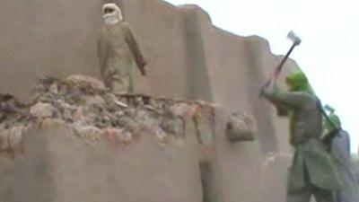 A suspected Islamic militant destroys a historic monument in Timbuktu