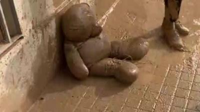 Teddy bear covered in mud slumped on pavement