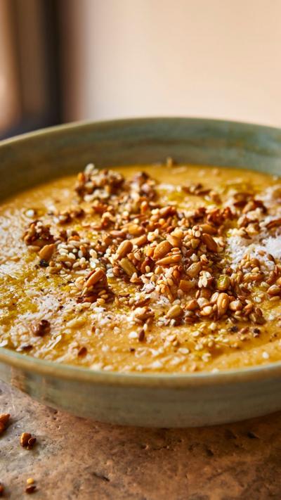 A green bowl with thick soup in and seeds sprinkled on top.