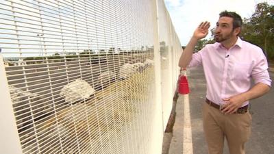 BBC reporter Tomos Morgan at a fence in Calais