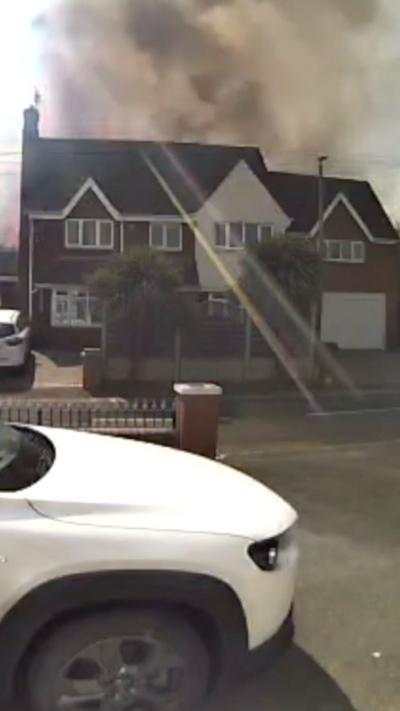 Flames and smoke are rising above a detached house. 