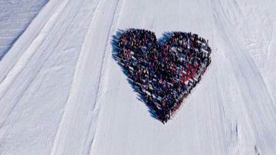 Skiers form the shape of a heart on a ski field from birds-eye-view