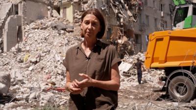 Sarah Rainsford standing in front of rubble