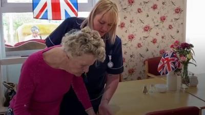 A carer helping a care home resident