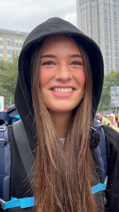 A girl with brown hair, wearing a black jacket.