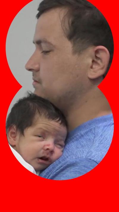 A newborn baby rests on a man's chest