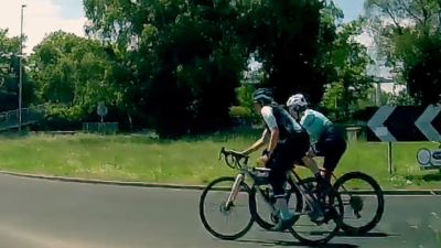 Two women cycling around a round about on dashcam