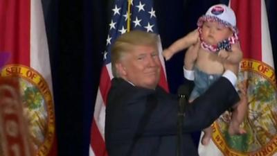 Donald Trump holding a baby on stage