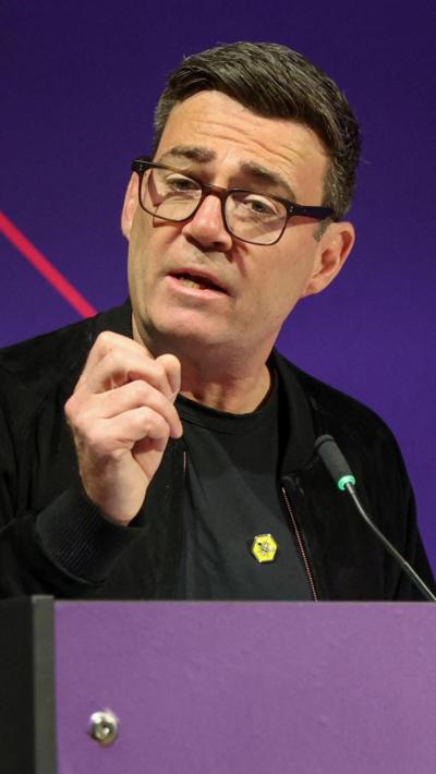 Andy Burnham wearing glasses and a black t-shirt and jacket