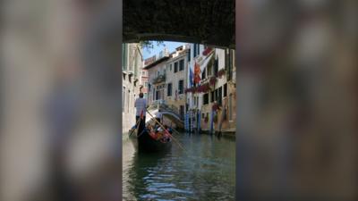 A gondola on a canal in Venice, with buildings either side of the water 