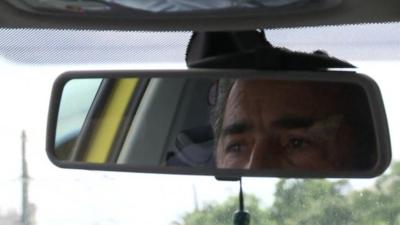 Taxi driver reflected in mirror