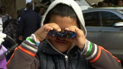 Migrant boy looking through binoculars