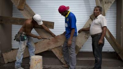 Men in Mexico board up a business in Vallarta