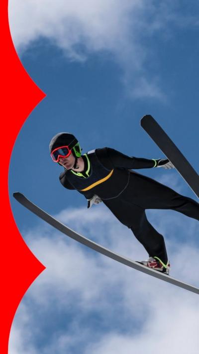 A man flyies through the air while ski jumping