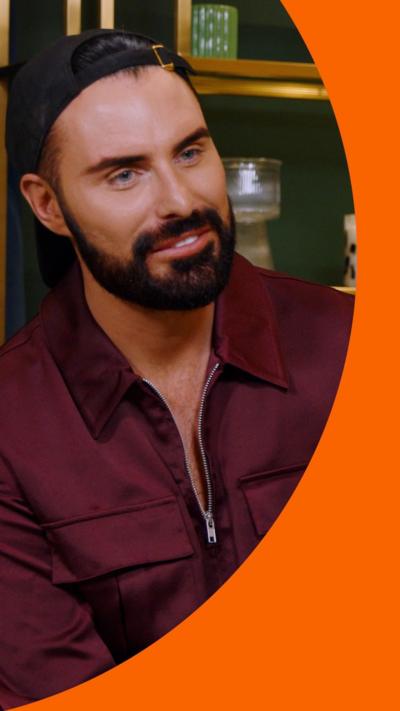 Rylan Clark wearing a black cap backwards on his head and wearing dark red top