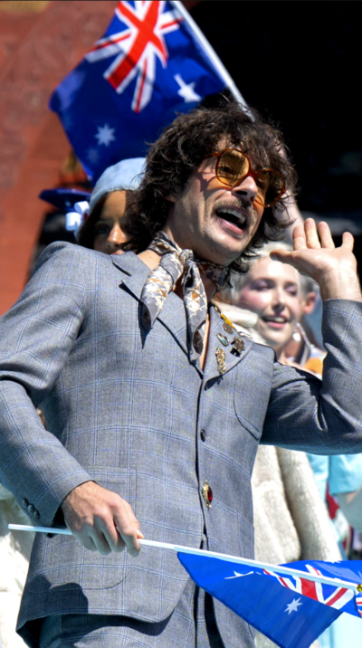 A man, Australia's Eurovision act Go-Jo, wearing a blue suit and holding an Australian flag