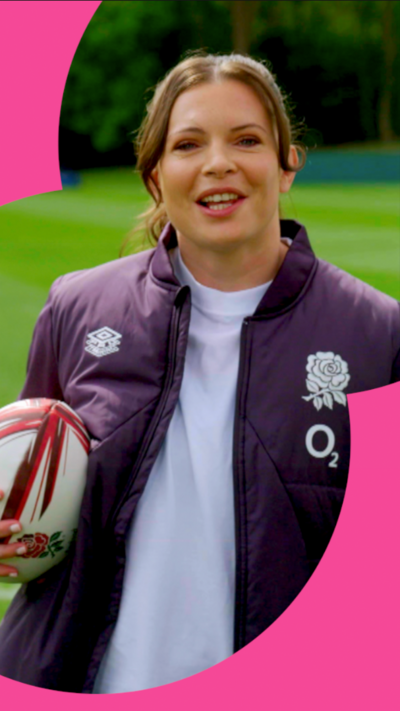 England rugby player Abbie Ward holding a rugby ball and leaning against a post
