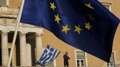 A protester waves a Greek flag at the entrance of the parliament building in Athens