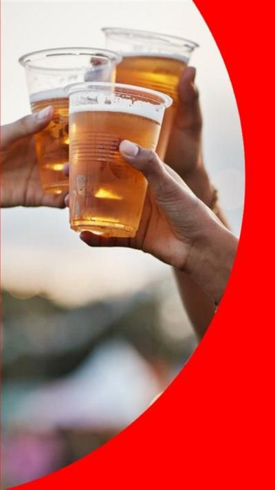 Three people's hands knock pints of beer together in plastic cups. 