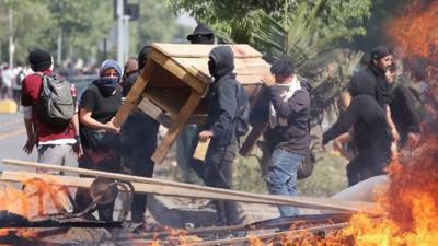 People burn objects as demonstrations against the increase of metro fares take place, in Santiago