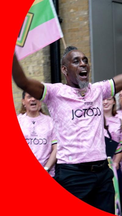A man in a pink shirt sings in King's Cross station
