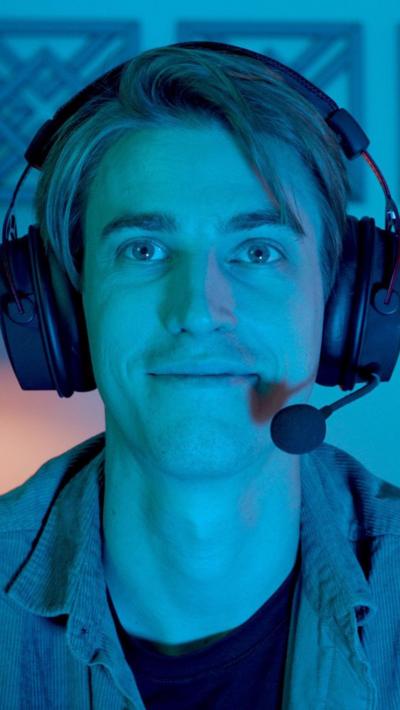 Young man bathed in blue light wearing a gaming headset