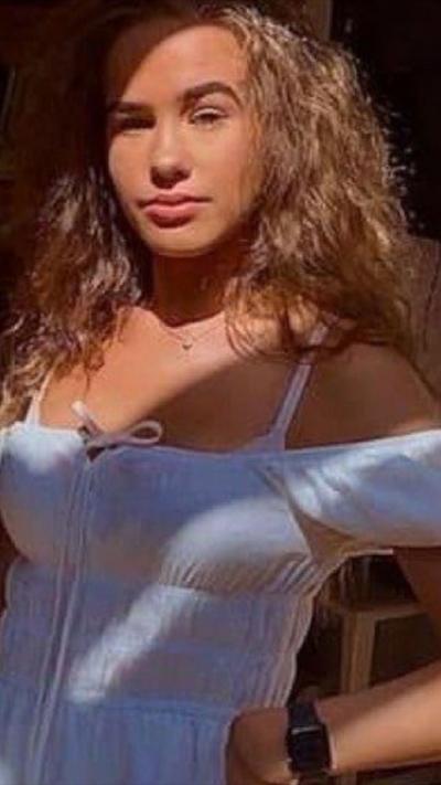 Young woman with long brown hair wearing a white summer dress
