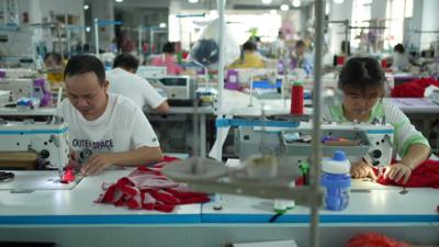 Two factory workers make clothing at sewing machines in China