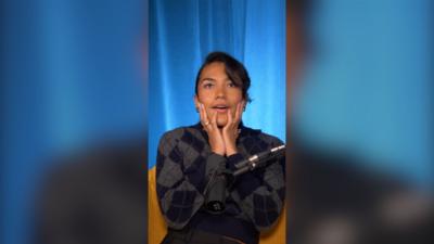 Olivia Dean with her hands on her face, sat in a chair