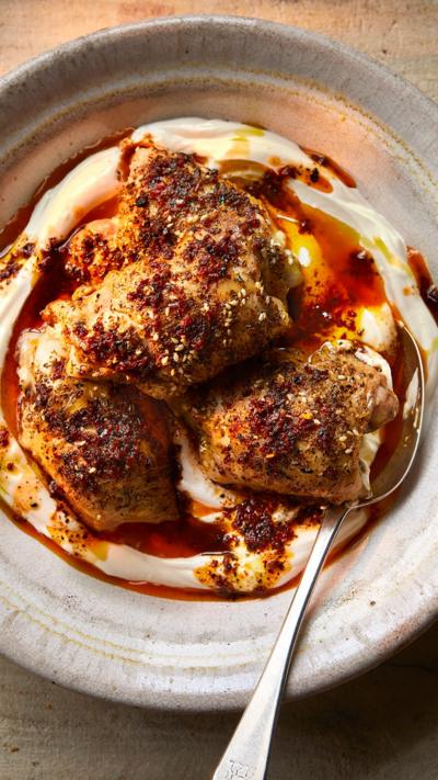 Chicken thighs on yoghurt in a bowl with a spoon on the side