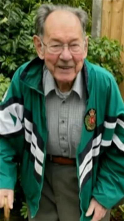An elderly man in a green coat.