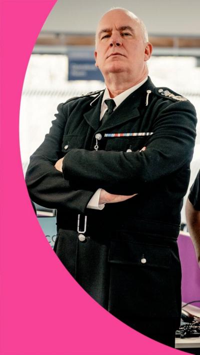A man stands in character dressed in a police uniform