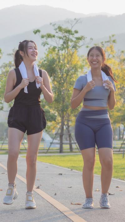Two young women in sports outfits walking together, both holding towels around their necks