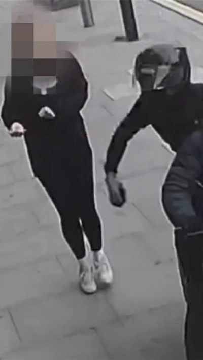 A motorcyclist grabbing a woman's phone on a London street