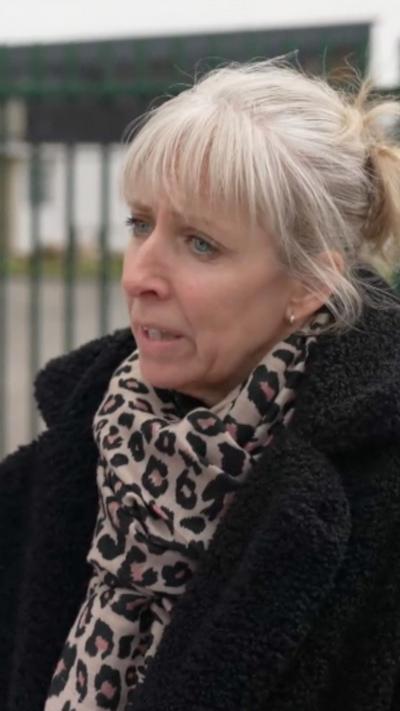 A woman with white hair looks to the left of the camera