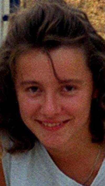 A young woman with long brown hair wearing a grey sleeveless top