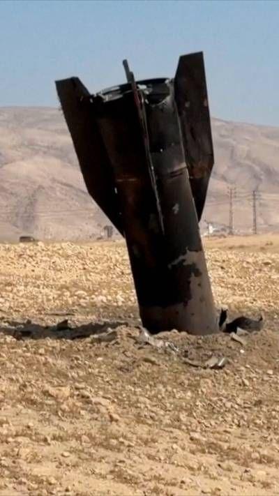 A man sits next to a ballistic missile partly submerged in the ground.