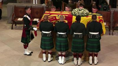 Members of the Royal Regiment of Scotland place Queen Elizabeth II's coffin on the catafalque