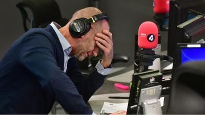 Evan Davis with his head in his hands