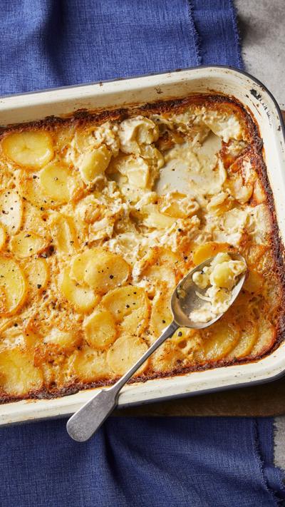 Top down view of a roasting tin with potatoes dauphinoise with a spoon in the side